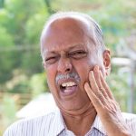 Elderly man with a toothache holding his face