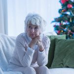 Older women sitting alone by Christmas Tree