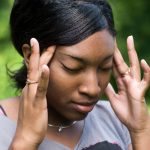 Black woman rubbing her temples, stressed