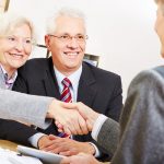 older man and woman in lawyers office shaking hands