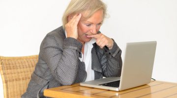 Older woman looking puzzled sitting in front of a laptop