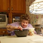 Older woman on kitchen eating fruit