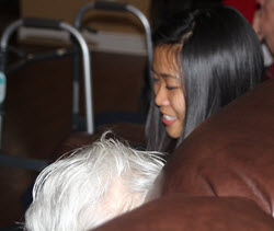 Young Asian adult sitting on a couch with an older Caucasian woman