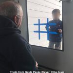 little boy playing a Tic Tac Toe on glass door with a senior